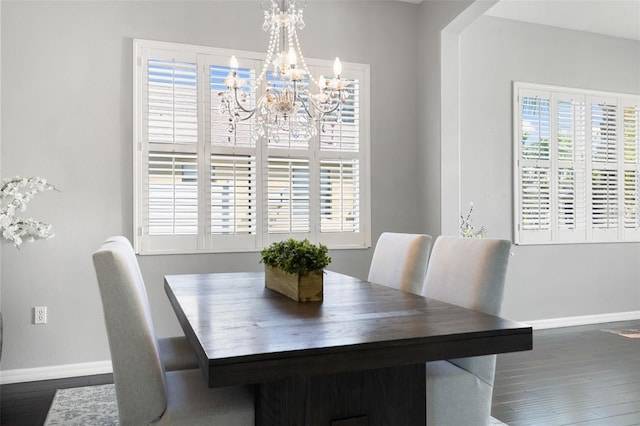 dining space featuring dark wood-type flooring and an inviting chandelier