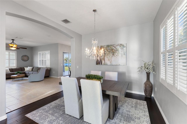 dining space with dark hardwood / wood-style floors and ceiling fan with notable chandelier