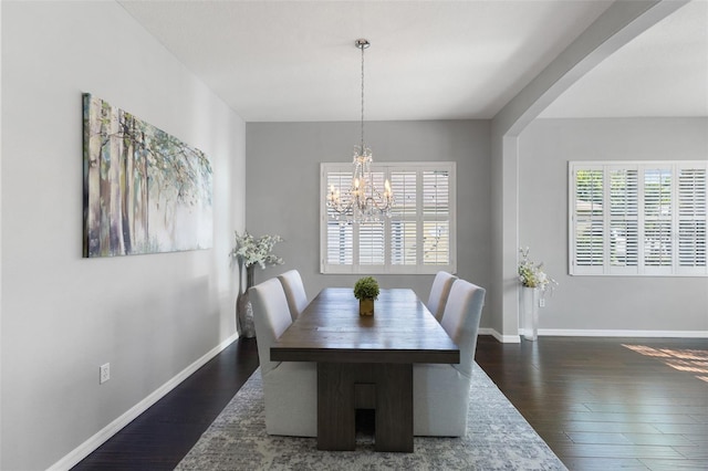 dining area with dark hardwood / wood-style flooring, a healthy amount of sunlight, and a notable chandelier