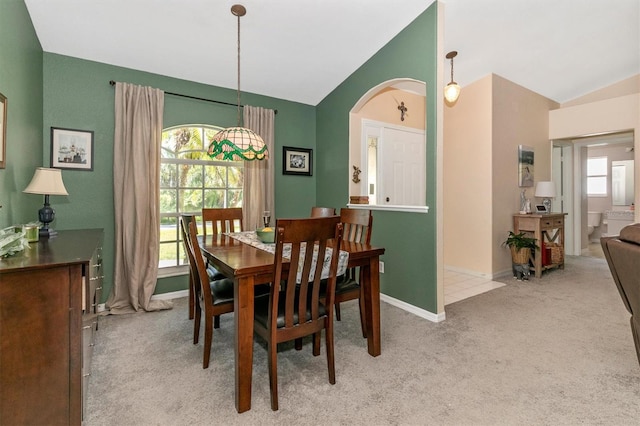 dining area featuring light colored carpet and vaulted ceiling