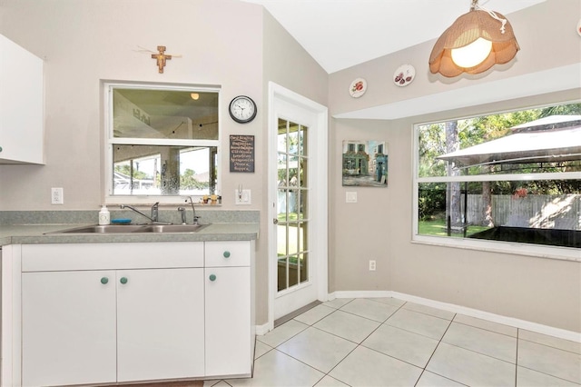 kitchen featuring white cabinets, lofted ceiling, light tile patterned flooring, and sink