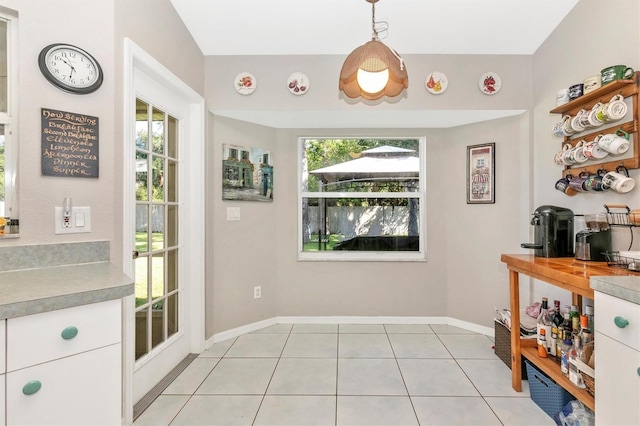 kitchen with plenty of natural light, white cabinets, hanging light fixtures, and light tile patterned floors