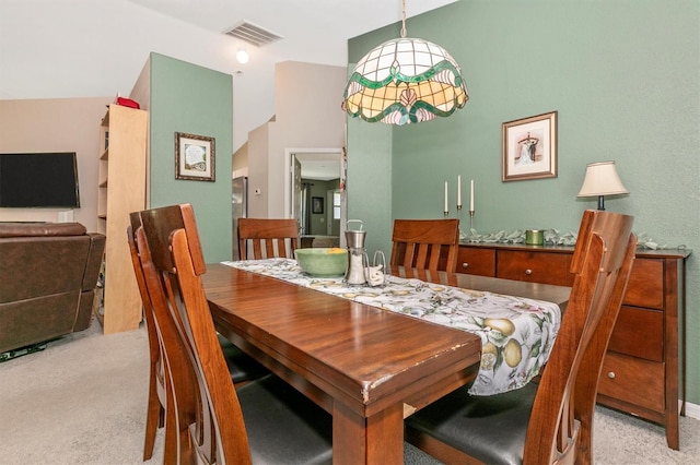 carpeted dining area with vaulted ceiling