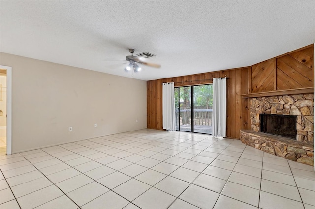 unfurnished living room featuring a textured ceiling, a fireplace, wooden walls, and ceiling fan