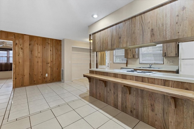 kitchen featuring light tile patterned flooring, wood walls, and sink