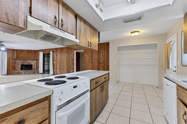 kitchen featuring ceiling fan, a stone fireplace, light tile patterned flooring, and white appliances