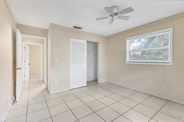 unfurnished bedroom with ceiling fan, a closet, crown molding, and light tile patterned floors