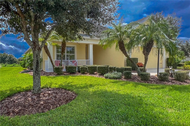 view of front of property featuring covered porch, a front yard, and a garage