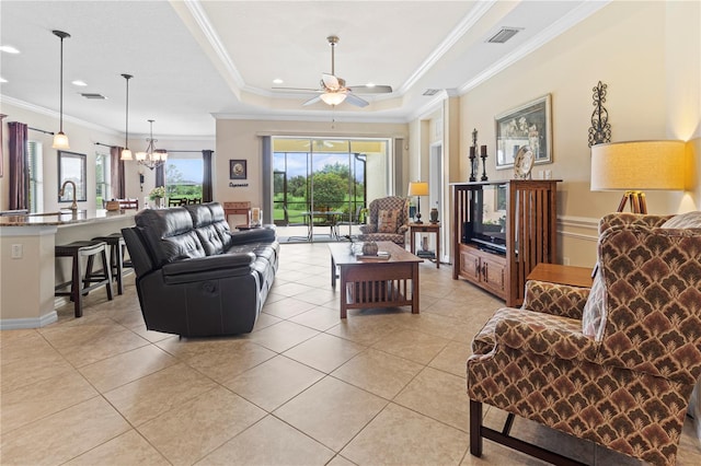 tiled living room featuring ceiling fan with notable chandelier, a raised ceiling, sink, and crown molding