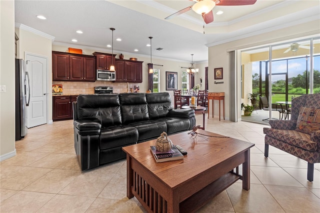 tiled living room featuring a healthy amount of sunlight, ceiling fan with notable chandelier, and ornamental molding