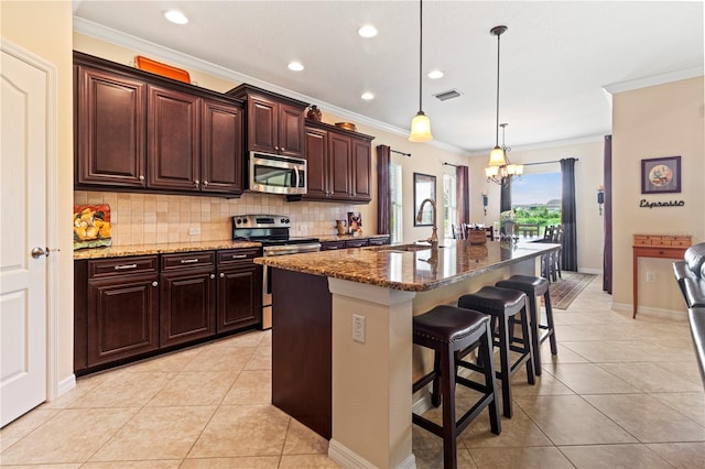 kitchen featuring dark stone countertops, a breakfast bar area, a center island with sink, and stainless steel appliances