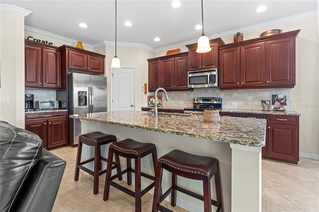 kitchen with pendant lighting, a center island with sink, appliances with stainless steel finishes, and decorative backsplash