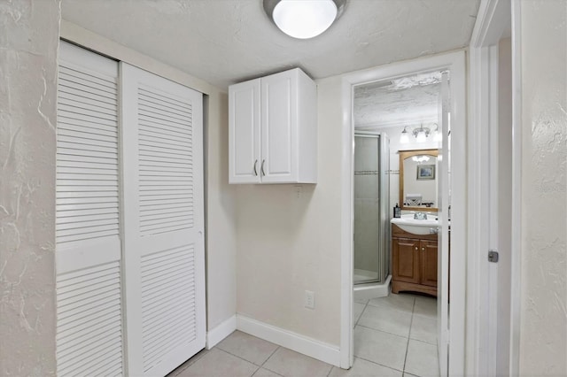 hall with light tile patterned flooring and a textured ceiling