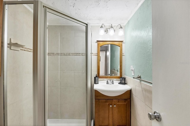 bathroom with vanity, a textured ceiling, tile walls, and a shower with shower door