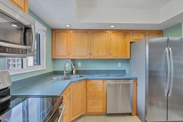 kitchen featuring appliances with stainless steel finishes, light tile patterned floors, a raised ceiling, and sink