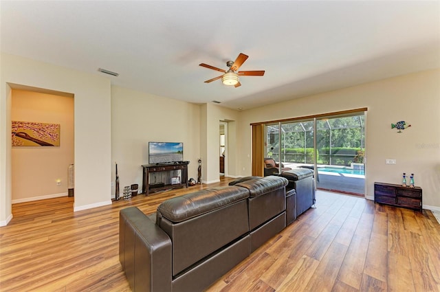 living room featuring light hardwood / wood-style floors, ceiling fan, and a fireplace