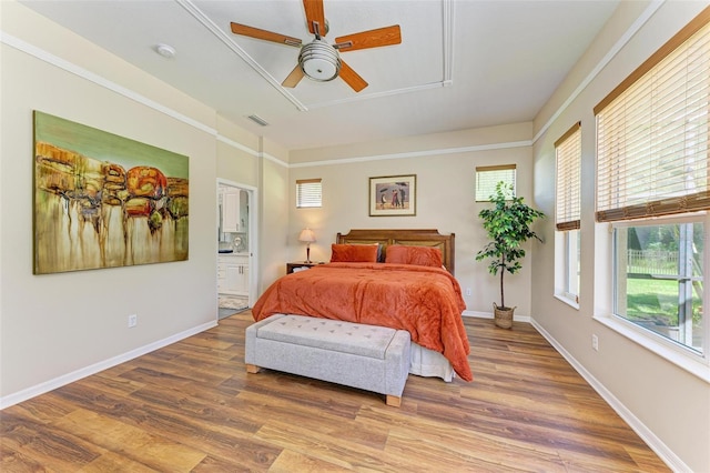 bedroom featuring crown molding, hardwood / wood-style floors, ceiling fan, and ensuite bath