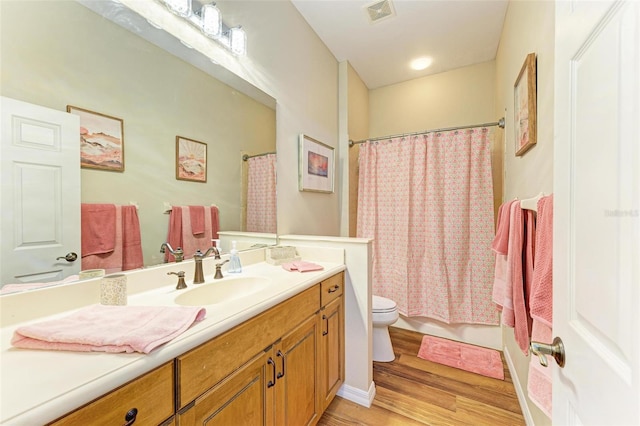 full bathroom with wood-type flooring, shower / tub combo with curtain, vanity, and toilet