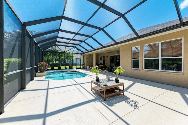 view of pool featuring glass enclosure, ceiling fan, and a patio area