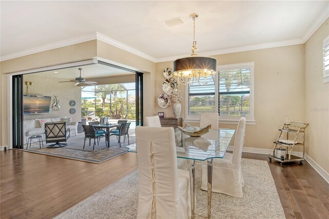 dining space featuring hardwood / wood-style flooring, ceiling fan with notable chandelier, and a healthy amount of sunlight