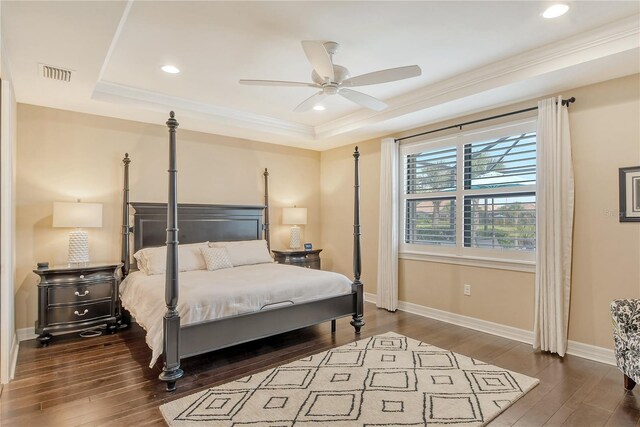 bedroom with a raised ceiling, ornamental molding, ceiling fan, and dark wood-type flooring