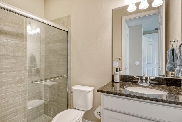 bathroom with walk in shower, vanity, and toilet