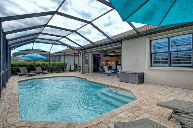 view of swimming pool featuring glass enclosure, ceiling fan, and a patio area