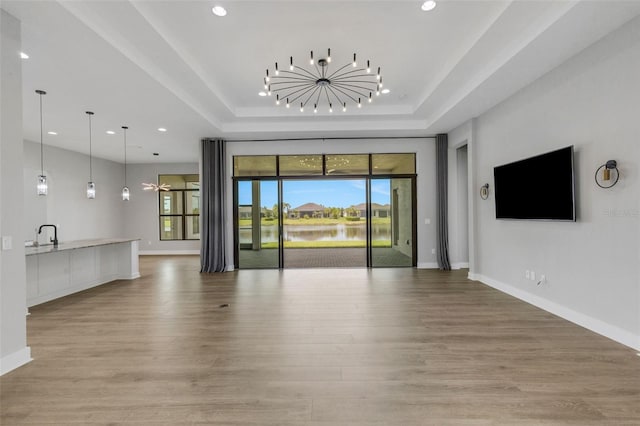 unfurnished living room featuring light wood-type flooring and a raised ceiling