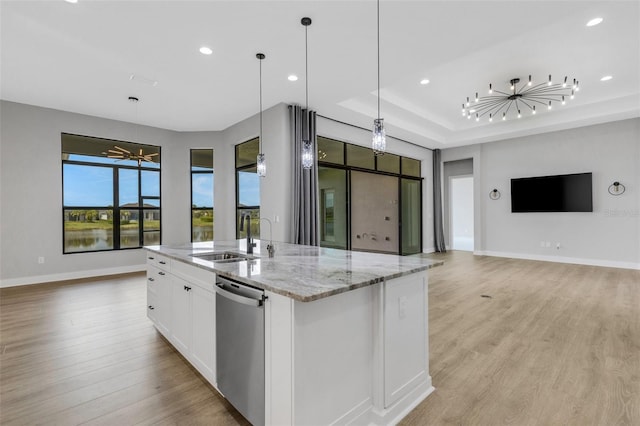 kitchen featuring dishwasher, light stone counters, white cabinetry, a center island with sink, and decorative light fixtures