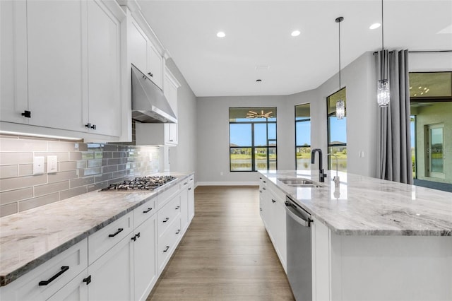 kitchen featuring a kitchen island with sink, sink, white cabinetry, appliances with stainless steel finishes, and decorative light fixtures