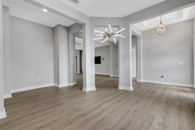 empty room featuring wood-type flooring and a chandelier