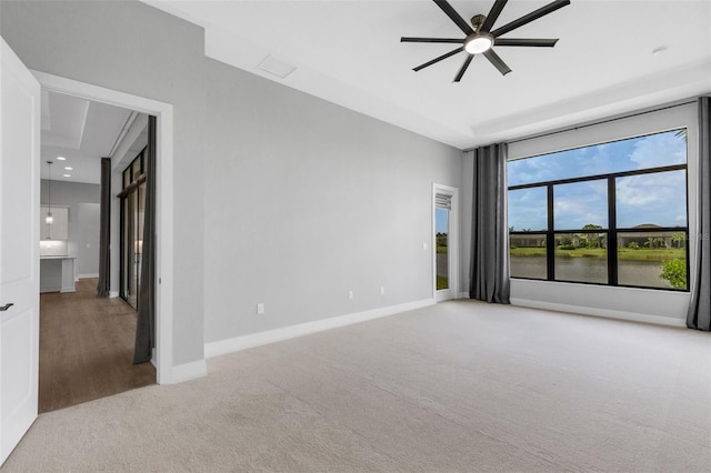 spare room with a water view, light carpet, and ceiling fan