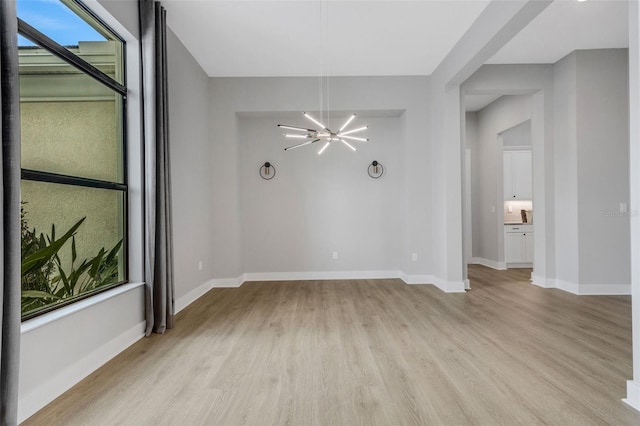 spare room featuring light hardwood / wood-style flooring and a notable chandelier