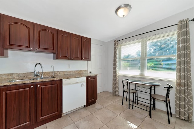 kitchen with light stone countertops, dishwasher, light tile patterned floors, and sink