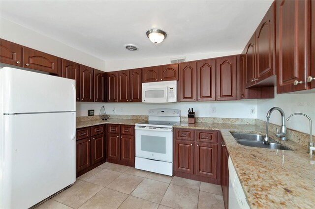 kitchen with light stone countertops, white appliances, sink, and light tile patterned floors