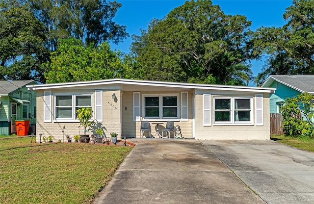 view of front facade with brick siding, concrete block siding, fence, and a front lawn