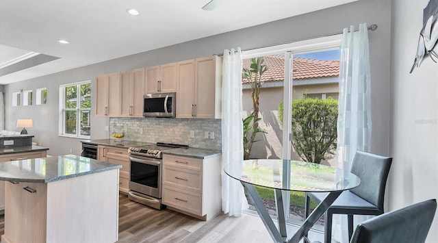 kitchen featuring decorative backsplash, wine cooler, a kitchen island, stainless steel appliances, and light wood-type flooring