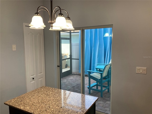 kitchen featuring a notable chandelier, light stone counters, a center island, and hanging light fixtures