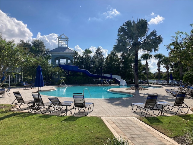 view of swimming pool featuring a patio, a lawn, and a water slide