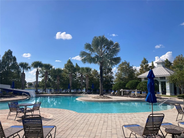 view of pool featuring a water slide and a patio area