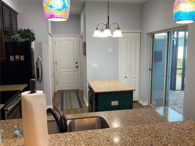 kitchen with black range with electric stovetop, stainless steel refrigerator with ice dispenser, a center island, an inviting chandelier, and light stone countertops