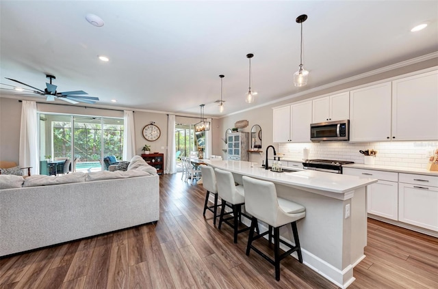3360 Chestertown Loop, Bradenton, FL 34211 - kitchen featuring a breakfast bar, a sink, open floor plan, crown molding, and stainless steel appliances