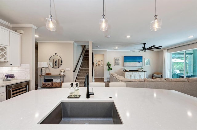 kitchen featuring pendant lighting, beverage cooler, sink, and ornamental molding