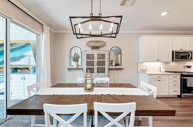 dining area featuring crown molding, light hardwood / wood-style flooring, and a chandelier