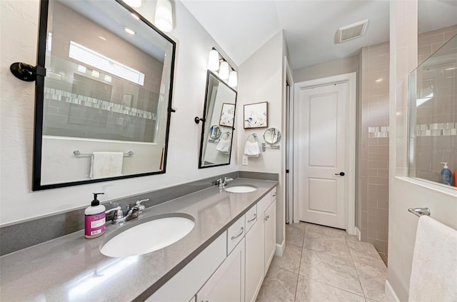 bathroom with a tile shower, tile patterned flooring, and vanity