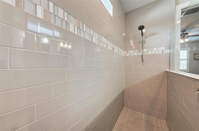 bathroom featuring ceiling fan, a wealth of natural light, and tiled shower