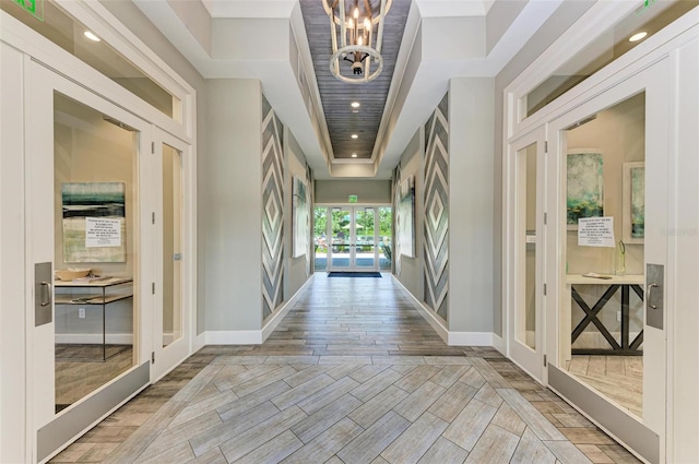 foyer entrance featuring light hardwood / wood-style flooring, a towering ceiling, a notable chandelier, and french doors