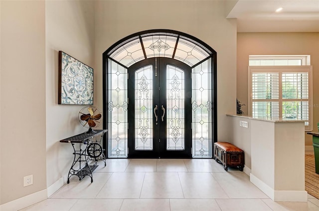 entrance foyer featuring french doors, light tile patterned floors, and plenty of natural light