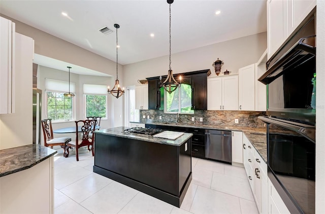 kitchen with a healthy amount of sunlight, stainless steel appliances, dark stone counters, and a kitchen island