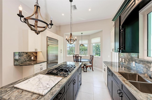 kitchen featuring appliances with stainless steel finishes, decorative backsplash, white cabinetry, and dark stone counters